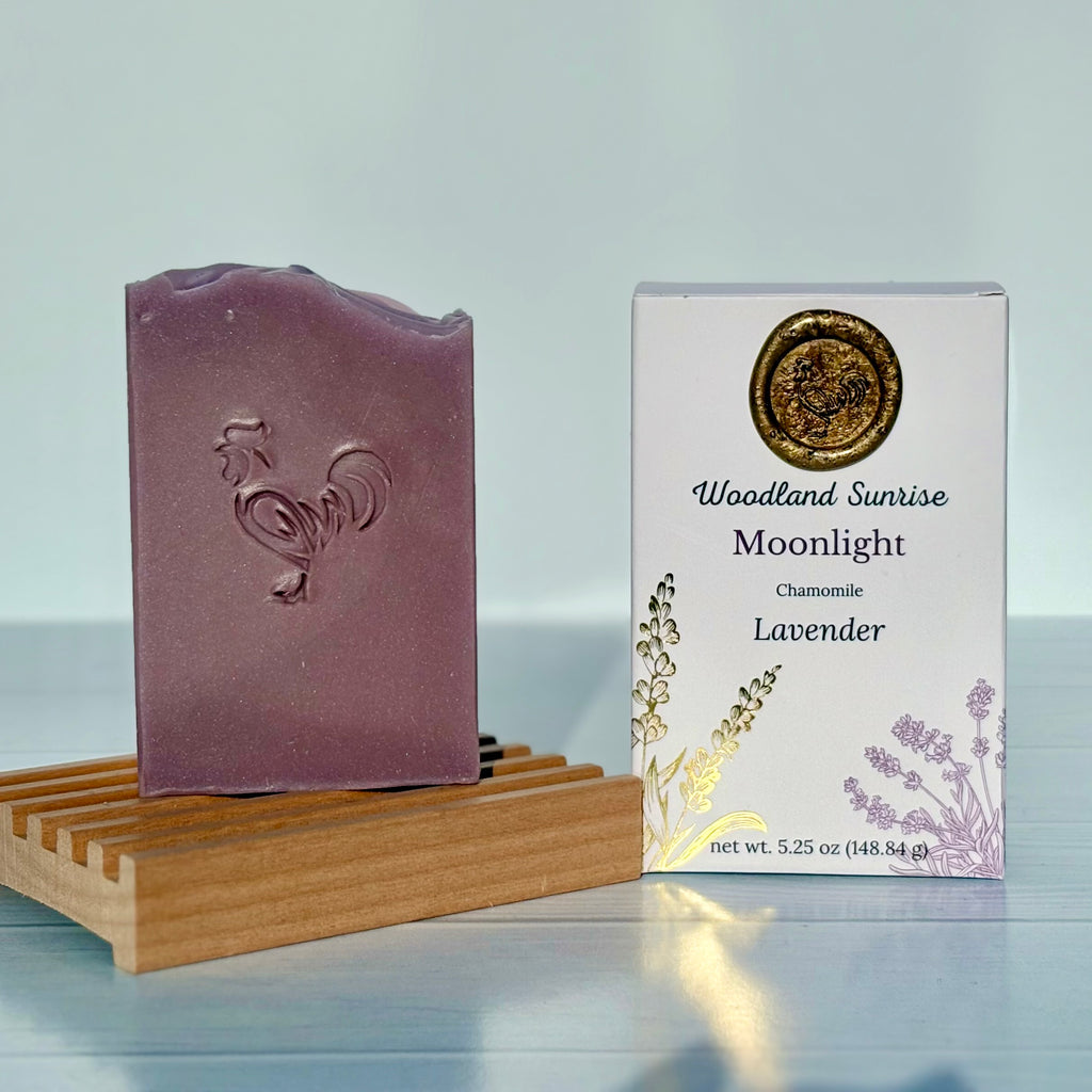 Purple soap bar on a wooden stand with a 'Woodland Sunrise Moonlight' packaging on a light gray background