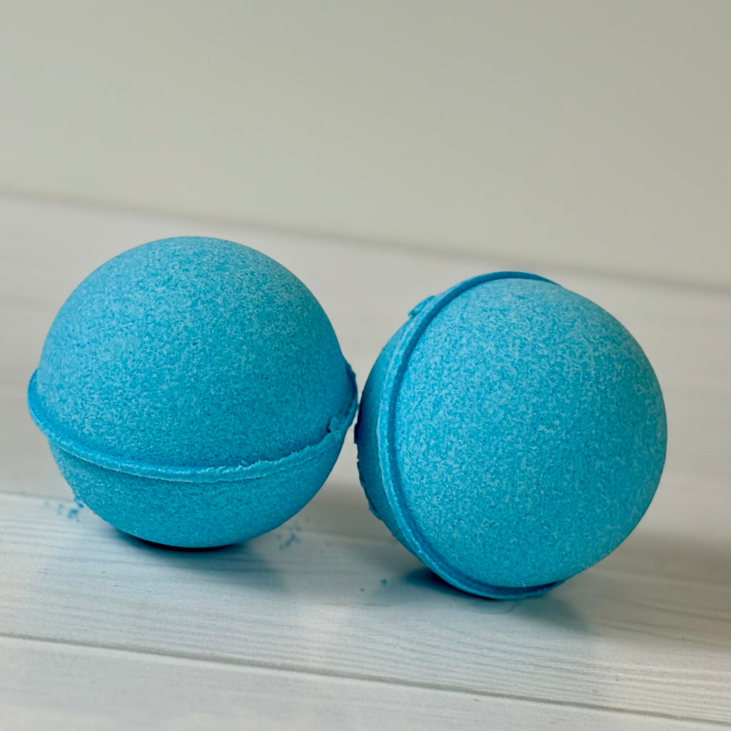 Two blue bath bombs on a light wooden surface