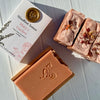 Two bars of soap with floral elements next to a box labeled 'Woodland Sunrise Mary's Garden'.