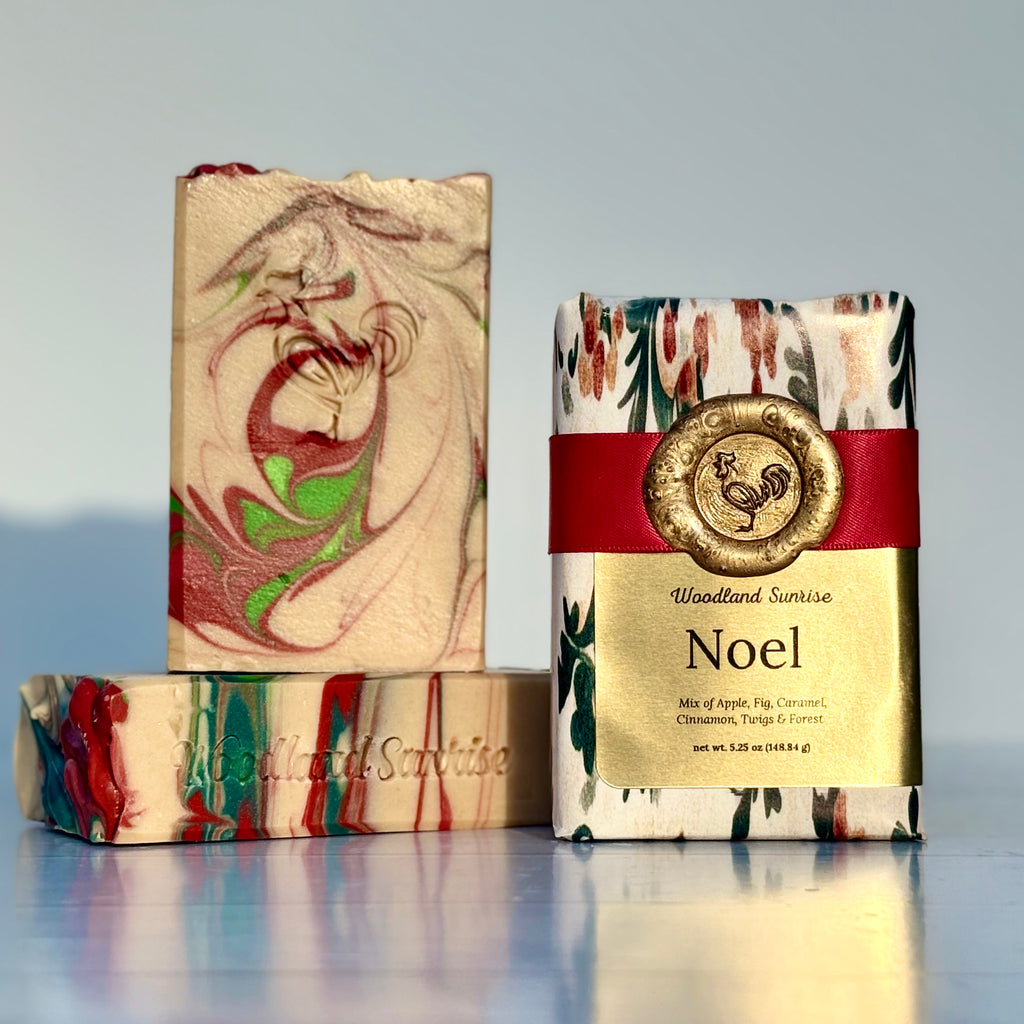 Three soap bars with decorative packaging on a reflective surface