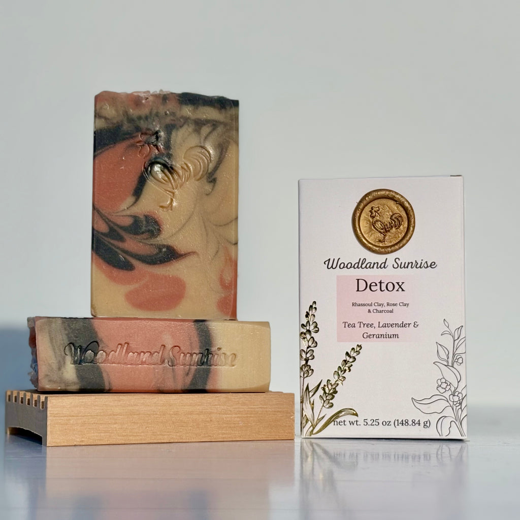 Two soap bars with a 'Woodland Sunrise' packaging on a reflective surface.