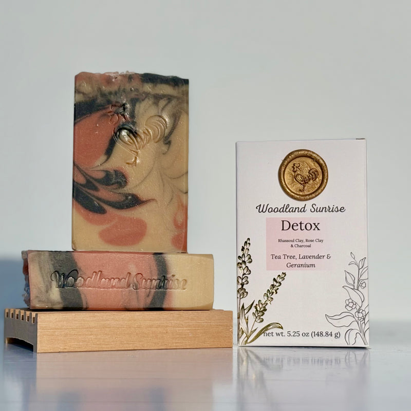 Two soap bars with a 'Woodland Sunrise' packaging on a reflective surface.