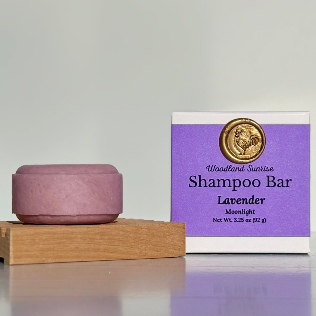 Purple shampoo bar with packaging labeled 'Woodland Sunrise Shampoo Bar Lavender Moonlight' on a gray background