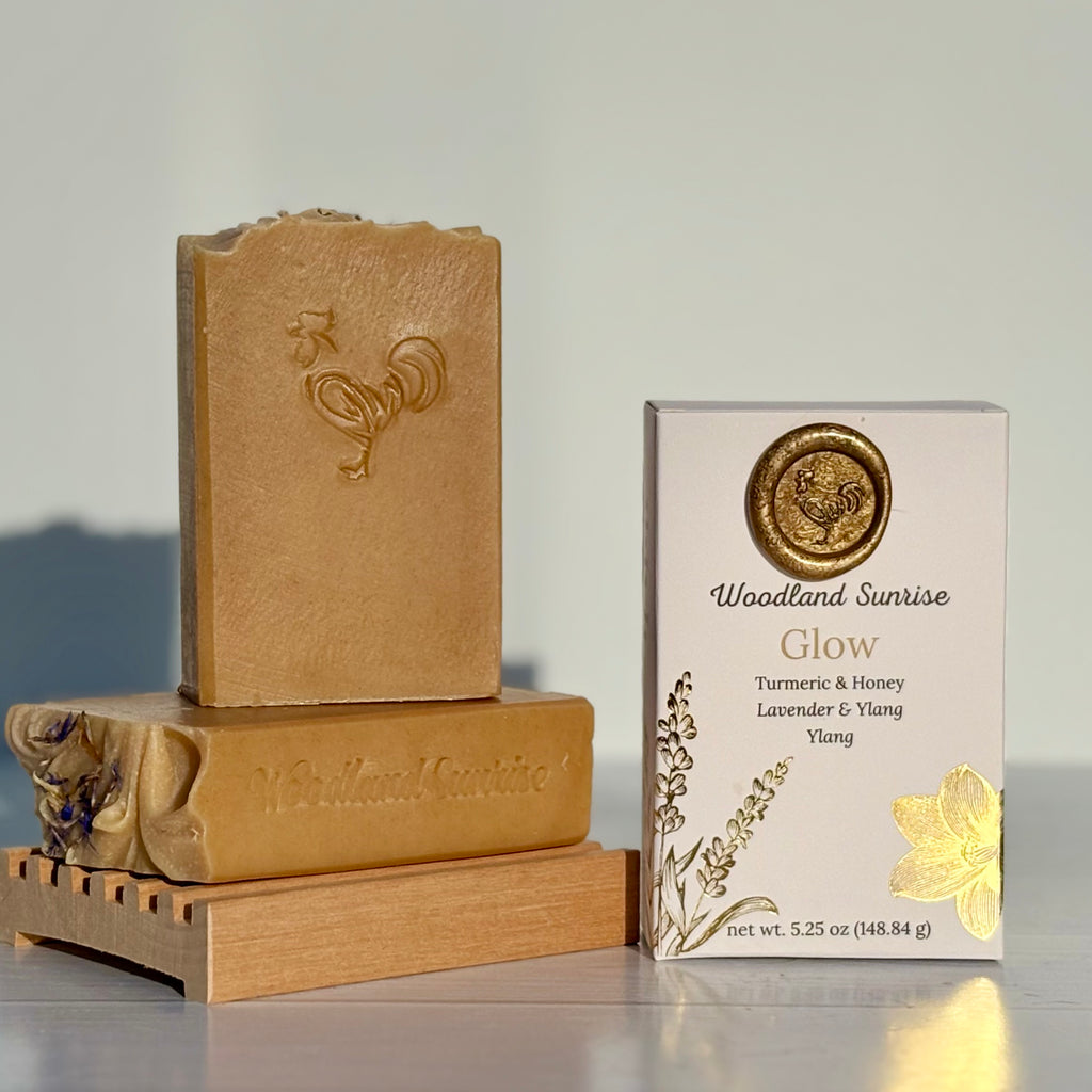 Two bars of Woodland Sunrise soap and their packaging on a gray background