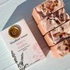 Bar soaps with floral elements next to their packaging labeled 'Woodland Sunrise Mary's Garden'.