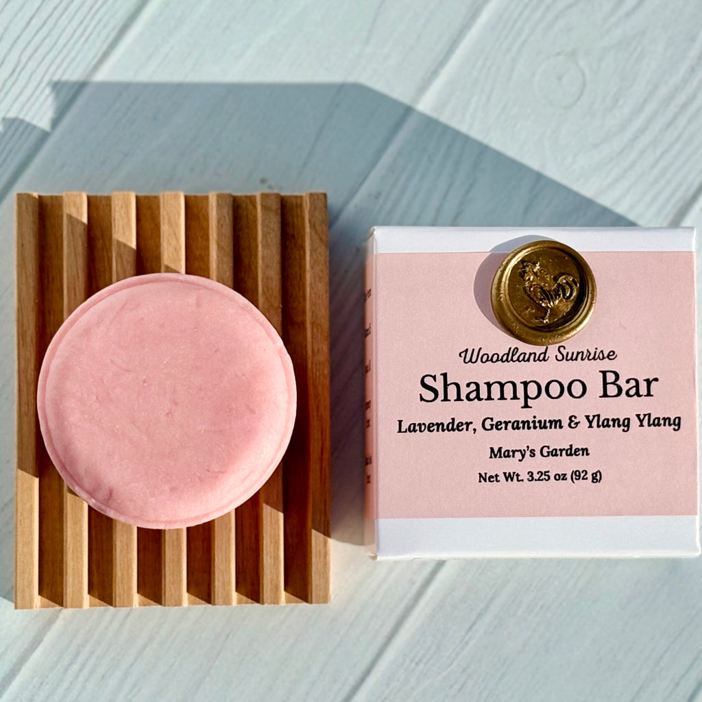 Pink shampoo bar on a wooden block with 'Woodland Sunrise' packaging on a light wooden surface