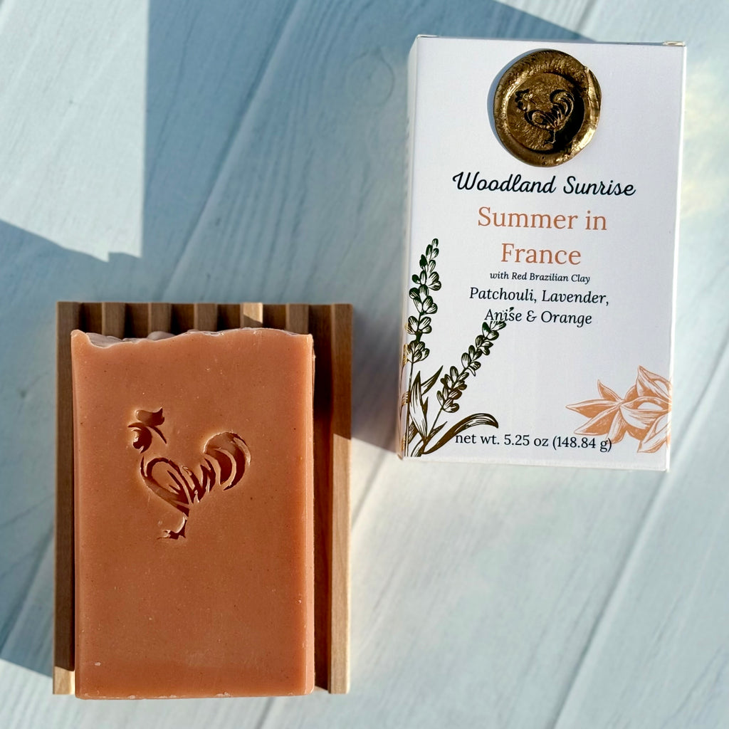 Bar of soap with rooster design next to its packaging on a light wooden surface