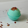 Green bath bomb with dried flowers on a white wooden surface