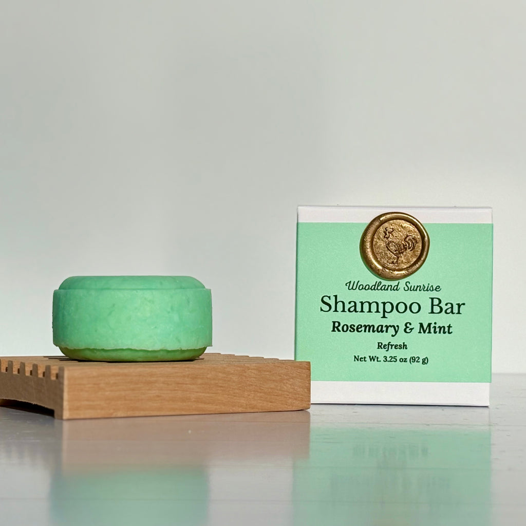 Green shampoo bar on a wooden block with a 'Woodland Sunrise' packaging in the background.