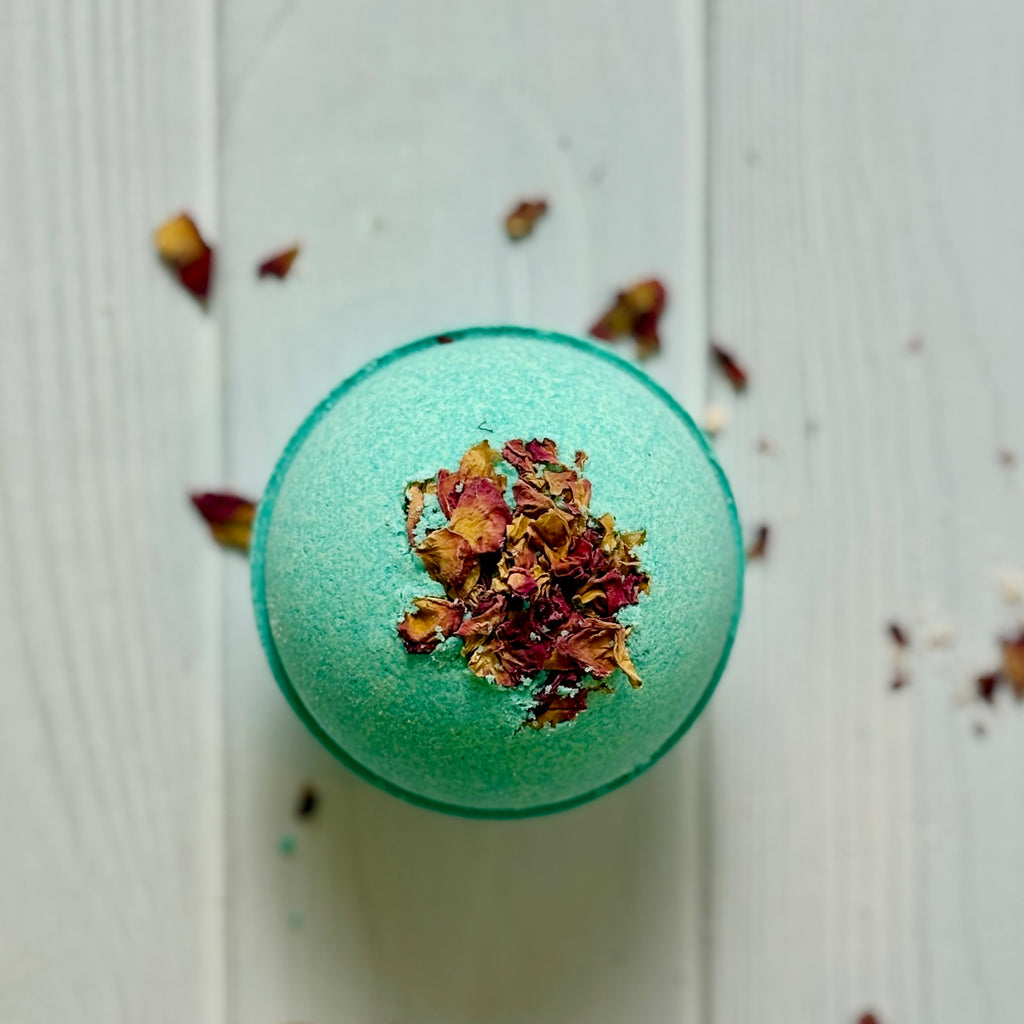 Green bath bomb with dried flowers on a light wooden surface