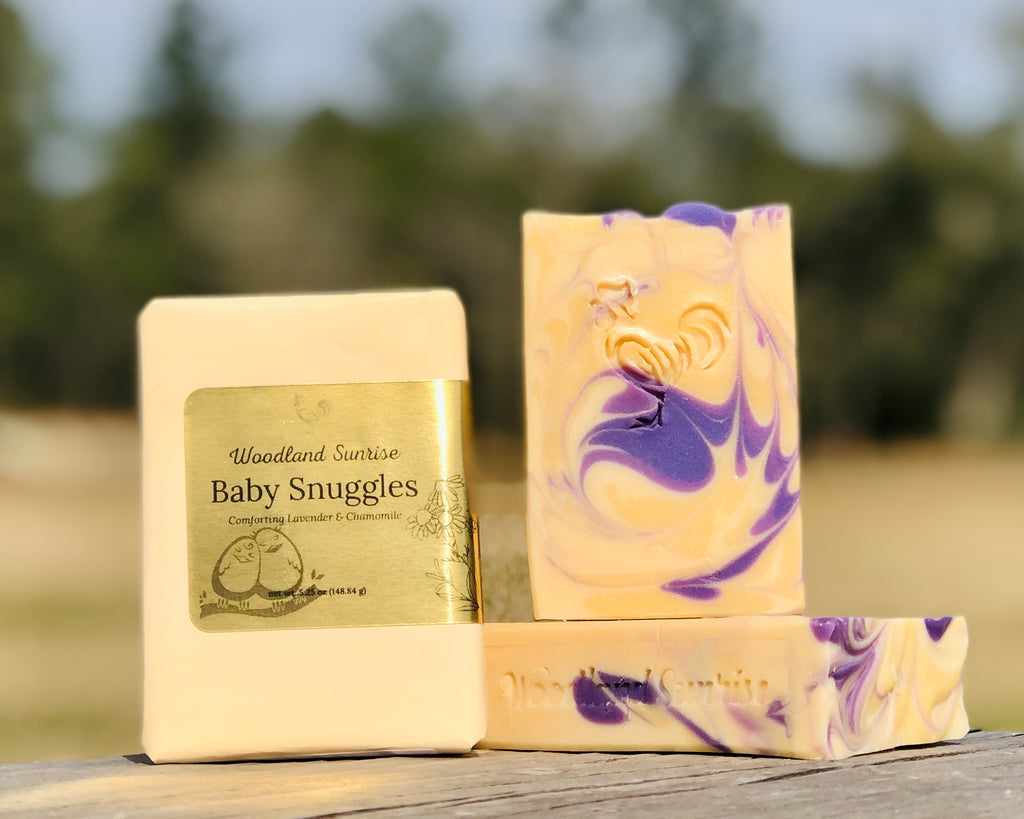 Baby Snuggles Handcrafted Bar Soap, pictured with paper packaging and display bar. 